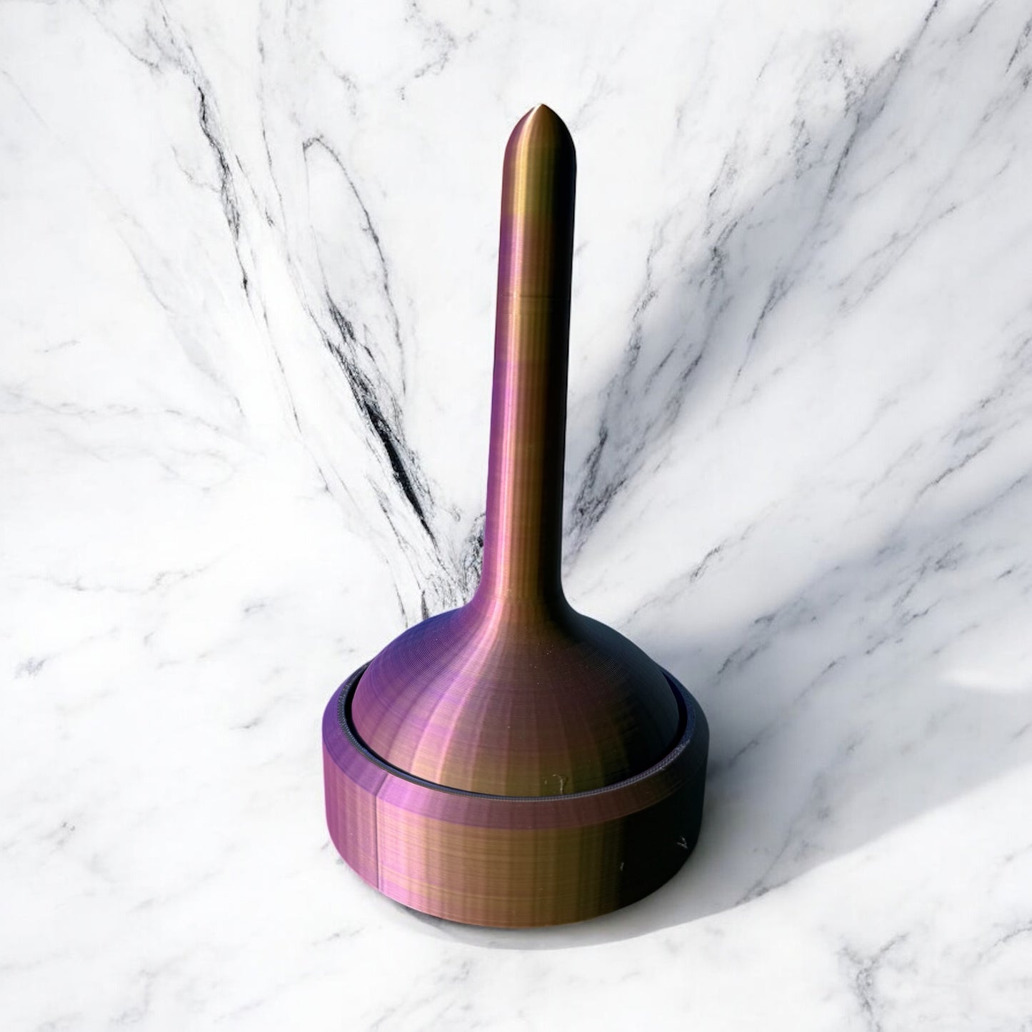 Iridescent rainbow yarn holder with tall center pole and wide circular base, photographed on white marble background, featuring metallic purple, gold, and bronze color-shifting finish